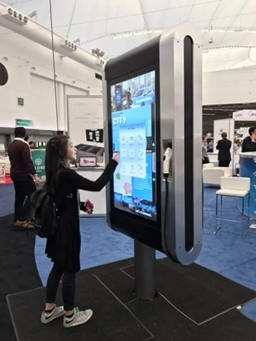 Side view of the physical ReCharged Smart-Hub prototype while a visitor interacts with its touchscreen